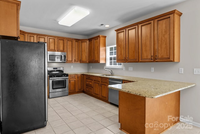 4519 Rock Stream Dr, Charlotte, NC 28269 - kitchen with appliances with stainless steel finishes, a peninsula, brown cabinetry, light tile patterned floors, and recessed lighting
