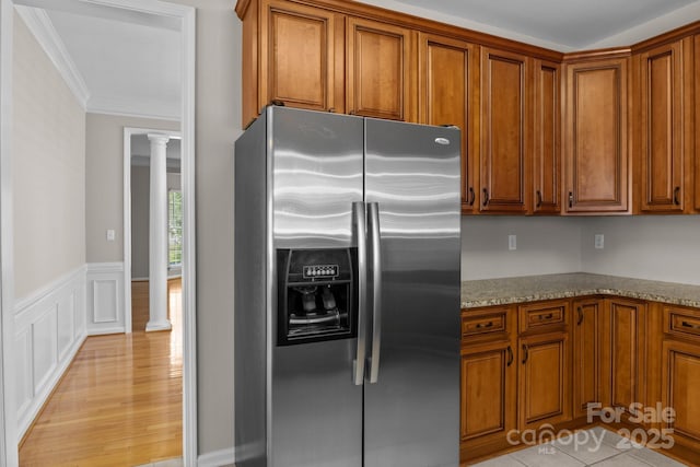 4519 Rock Stream Dr, Charlotte, NC 28269 - kitchen with stainless steel fridge with ice dispenser, decorative columns, brown cabinetry, light stone countertops, and ornamental molding