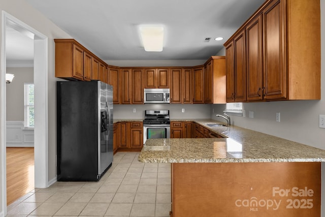 4519 Rock Stream Dr, Charlotte, NC 28269 - kitchen with stainless steel appliances, brown cabinets, a peninsula, light stone counters, and recessed lighting