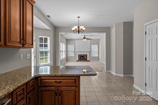 4519 Rock Stream Dr, Charlotte, NC 28269 - kitchen featuring a chandelier, light tile patterned floors, a ceiling fan, a fireplace, and a peninsula