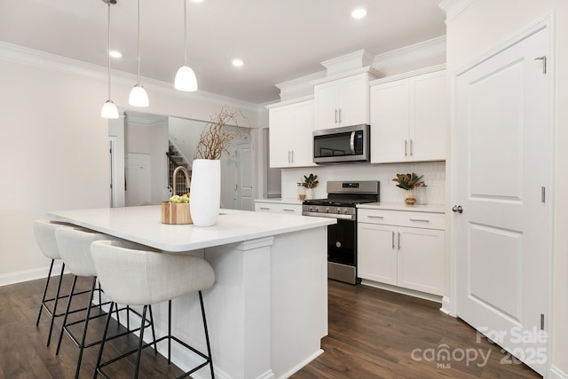 123 S Shayna Rd, Troutman, NC 28166 - kitchen featuring appliances with stainless steel finishes, crown molding, an island with sink, white cabinetry, and decorative backsplash