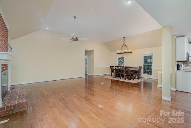 140 Rustic Way Ln, Mooresville, NC 28117 - unfurnished living room featuring lofted ceiling, light wood finished floors, a fireplace, ceiling fan, and a chandelier