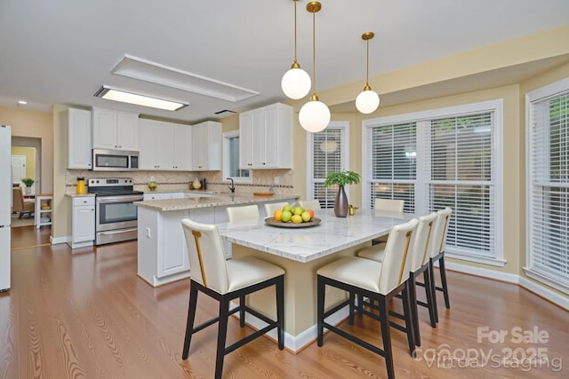 140 Rustic Way Ln, Mooresville, NC 28117 - kitchen featuring stainless steel appliances, a kitchen island, wood finished floors, backsplash, and a breakfast bar area