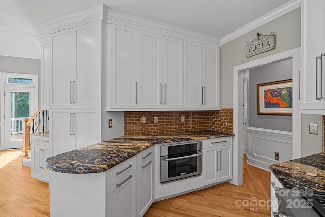15724 Eagleview Dr, Charlotte, NC 28278 - kitchen featuring oven, light wood finished floors, white cabinets, dark stone countertops, and ornamental molding