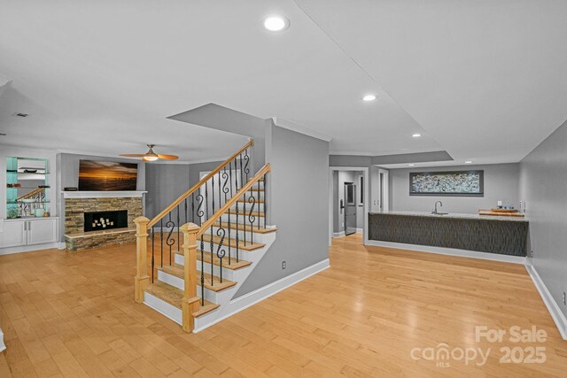 15724 Eagleview Dr, Charlotte, NC 28278 - staircase with wood finished floors, a stone fireplace, a ceiling fan, recessed lighting, and wet bar