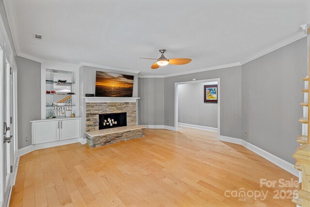 15724 Eagleview Dr, Charlotte, NC 28278 - unfurnished living room featuring a ceiling fan, light wood-style flooring, a stone fireplace, ornamental molding, and stairway
