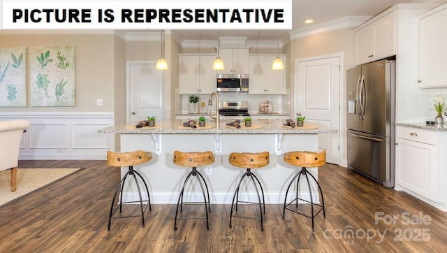502 York Rd, Troutman, NC 28166 - kitchen with stainless steel appliances, white cabinets, a breakfast bar area, ornamental molding, and a center island with sink