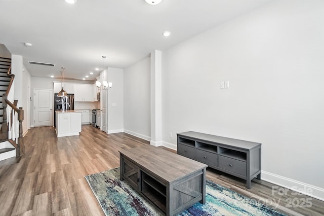 334 Ladybird Ln, Pineville, NC 28134 - unfurnished living room with stairway, light wood-style flooring, recessed lighting, and a chandelier