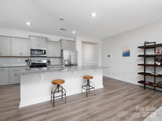 4177 Steel Way, Sherrills Ford, NC 28673 - kitchen with stainless steel appliances, gray cabinetry, a kitchen island with sink, a breakfast bar area, and ornamental molding
