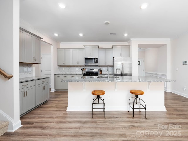 4177 Steel Way, Sherrills Ford, NC 28673 - kitchen with appliances with stainless steel finishes, gray cabinets, decorative backsplash, a breakfast bar, and light wood-style flooring