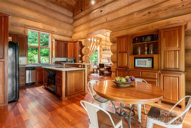 303 Flying Hawk Trl, Waynesville, NC 28786 - kitchen featuring black appliances, rustic walls, brown cabinets, dark wood-style flooring, and a center island