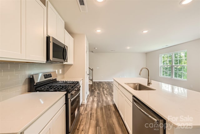 136 Dorian Pl, Troutman, NC 28166 - kitchen featuring appliances with stainless steel finishes, dark wood-style floors, tasteful backsplash, recessed lighting, and white cabinetry