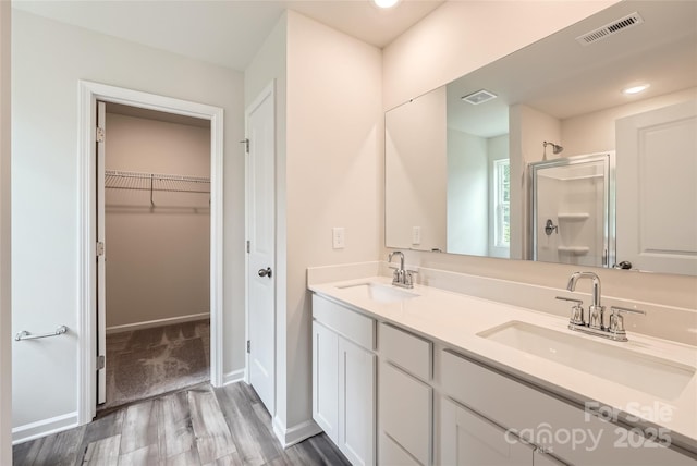 136 Dorian Pl, Troutman, NC 28166 - bathroom with a shower stall, wood finished floors, double vanity, and a spacious closet