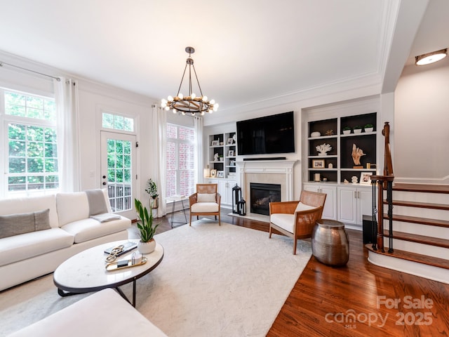 3036 Luke Crossing Dr, Charlotte, NC 28226 - living area featuring dark wood finished floors, a chandelier, stairway, a fireplace with flush hearth, and ornamental molding