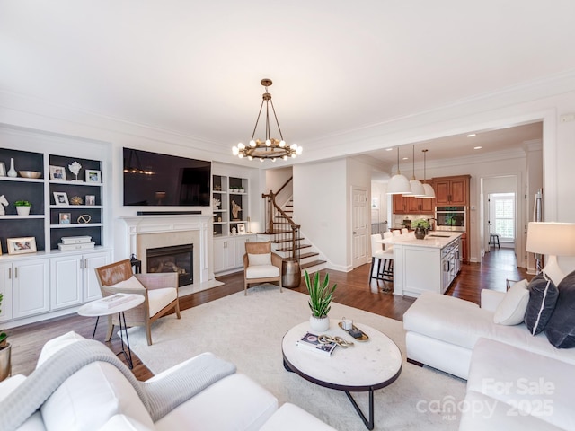 3036 Luke Crossing Dr, Charlotte, NC 28226 - living room featuring crown molding, stairs, dark wood-style flooring, a fireplace, and a chandelier