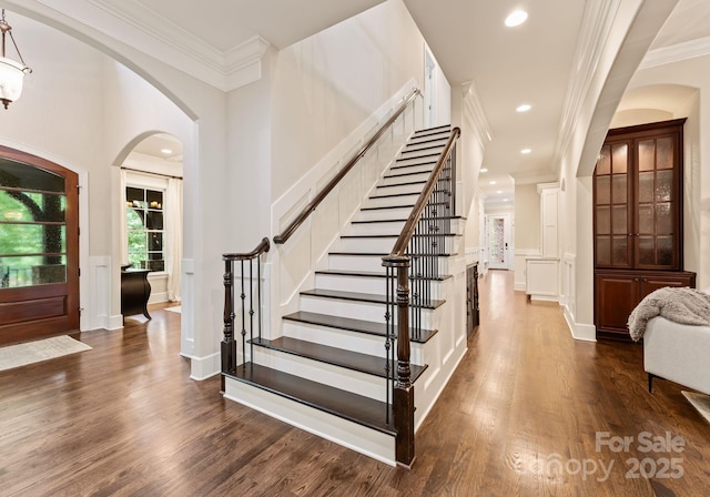 408 Covington Xing, Matthews, NC 28104 - entrance foyer with dark wood-style flooring, a decorative wall, ornamental molding, stairway, and arched walkways