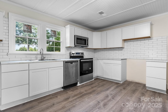 921 Spencer Rd NE, Conover, NC 28613 - kitchen with stainless steel appliances, ornamental molding, backsplash, dark wood-style flooring, and white cabinets