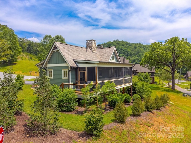 396 River Club Dr, Cullowhee, NC 28723 - back of property with a sunroom, board and batten siding, a lawn, a chimney, and roof with shingles