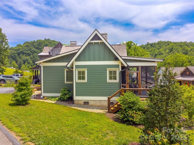 396 River Club Dr, Cullowhee, NC 28723 - back of property with board and batten siding, a sunroom, a lawn, a chimney, and a shingled roof