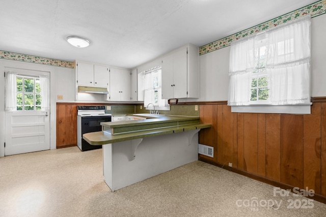 1520 21st Ave NE, Hickory, NC 28601 - kitchen with electric stove, under cabinet range hood, a wainscoted wall, a peninsula, and white cabinets