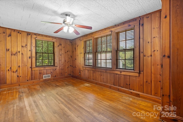 1520 21st Ave NE, Hickory, NC 28601 - unfurnished room featuring light wood-style flooring, a ceiling fan, and wood walls