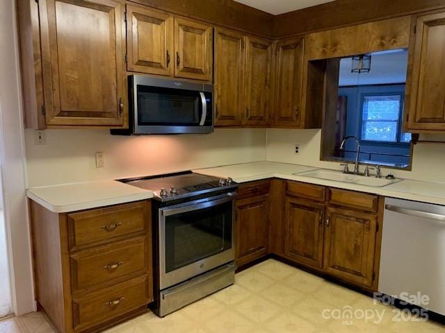 209 8th Ave NW, Hickory, NC 28601 - kitchen featuring stainless steel appliances, light countertops, light flooring, and brown cabinetry