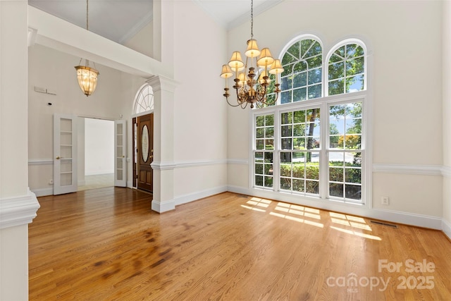 2241 Flagstick Dr, Matthews, NC 28104 - unfurnished dining area with a chandelier, ornamental molding, a towering ceiling, healthy amount of natural light, and wood finished floors