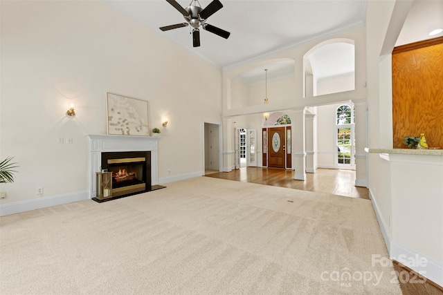 2241 Flagstick Dr, Matthews, NC 28104 - unfurnished living room featuring carpet floors, a towering ceiling, a glass covered fireplace, ceiling fan, and crown molding