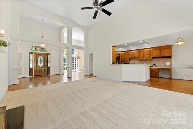2241 Flagstick Dr, Matthews, NC 28104 - entrance foyer with decorative columns, ceiling fan, a towering ceiling, light wood-style flooring, and light colored carpet