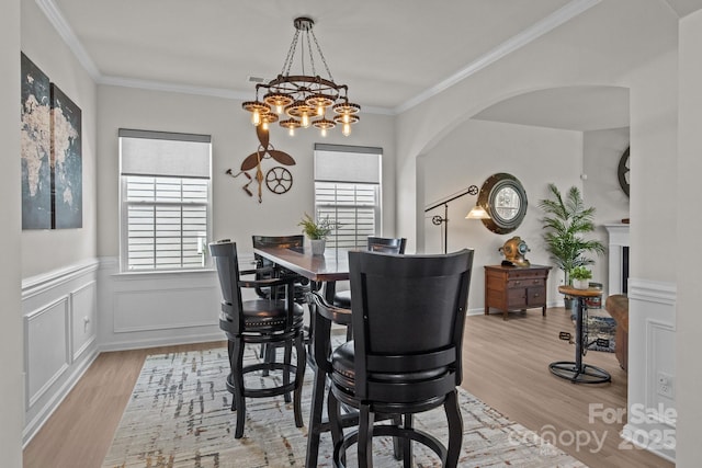 169 Rooster Tail Ln, Troutman, NC 28166 - dining space featuring plenty of natural light, wood finished floors, arched walkways, a wainscoted wall, and ornamental molding