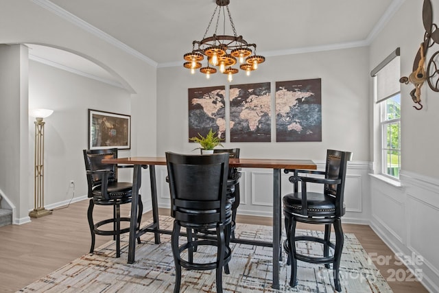 169 Rooster Tail Ln, Troutman, NC 28166 - dining room featuring arched walkways, light wood finished floors, a chandelier, and ornamental molding