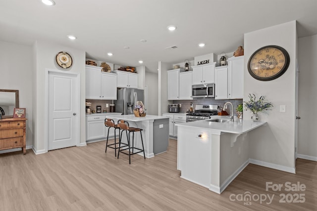 169 Rooster Tail Ln, Troutman, NC 28166 - kitchen featuring stainless steel appliances, a breakfast bar area, light wood finished floors, tasteful backsplash, and recessed lighting