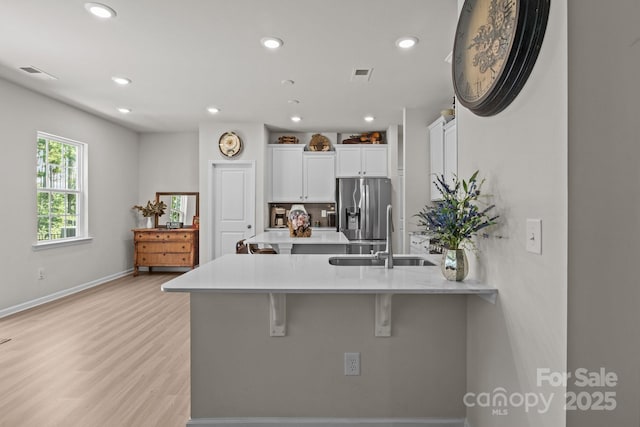 169 Rooster Tail Ln, Troutman, NC 28166 - kitchen featuring stainless steel fridge, a peninsula, a kitchen bar, white cabinets, and light countertops