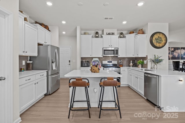 169 Rooster Tail Ln, Troutman, NC 28166 - kitchen featuring stainless steel appliances, white cabinets, backsplash, a kitchen bar, and recessed lighting