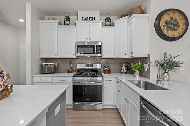 169 Rooster Tail Ln, Troutman, NC 28166 - kitchen featuring stainless steel appliances, white cabinetry, backsplash, light wood-style flooring, and light stone countertops