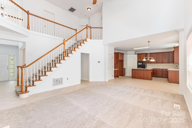 14333 Maclauren Ln, Huntersville, NC 28078 - unfurnished living room featuring a high ceiling, stairs, a chandelier, light carpet, and light tile patterned floors