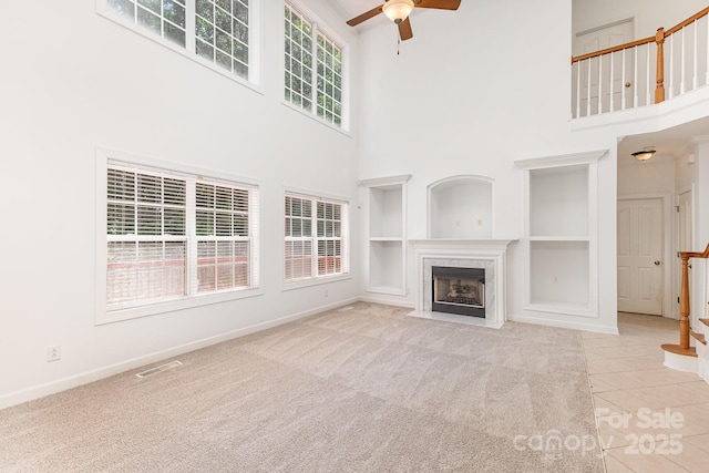 14333 Maclauren Ln, Huntersville, NC 28078 - unfurnished living room featuring a towering ceiling, built in shelves, ceiling fan, a fireplace, and tile patterned floors