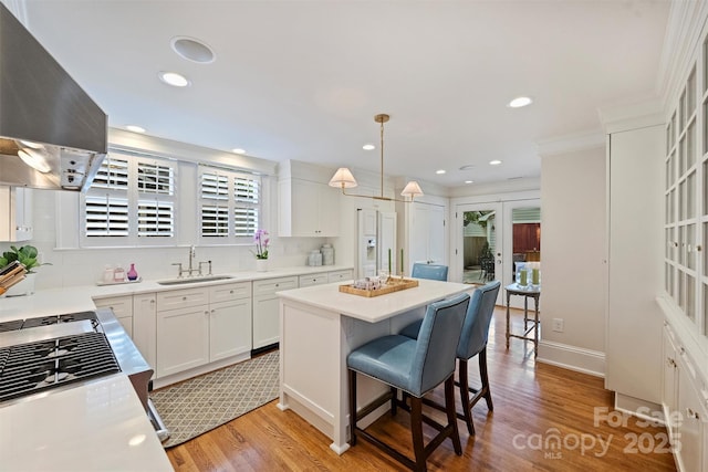 726 E Kingston Ave, Charlotte, NC 28203 - kitchen with wall chimney exhaust hood, light wood finished floors, tasteful backsplash, a center island, and recessed lighting