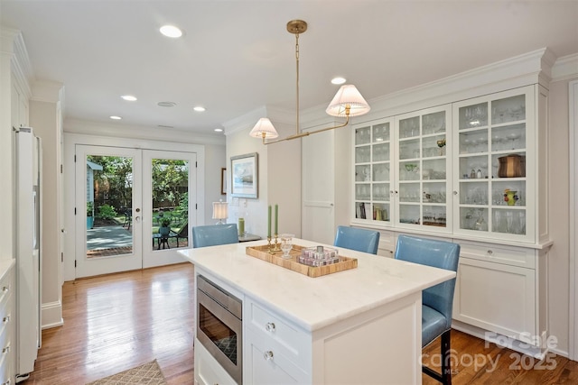 726 E Kingston Ave, Charlotte, NC 28203 - kitchen featuring stainless steel microwave, crown molding, glass insert cabinets, white cabinetry, and a kitchen island