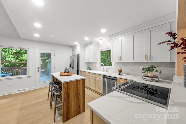 3519 Campbell Dr, Charlotte, NC 28205 - kitchen featuring appliances with stainless steel finishes, tasteful backsplash, light wood-style flooring, recessed lighting, and light stone countertops