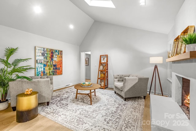 3519 Campbell Dr, Charlotte, NC 28205 - living area featuring wood finished floors, a lit fireplace, a skylight, and high vaulted ceiling