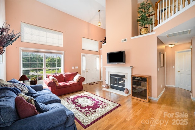 220 Holmes Ct, Concord, NC 28027 - living area featuring wood finished floors, a towering ceiling, and a glass covered fireplace