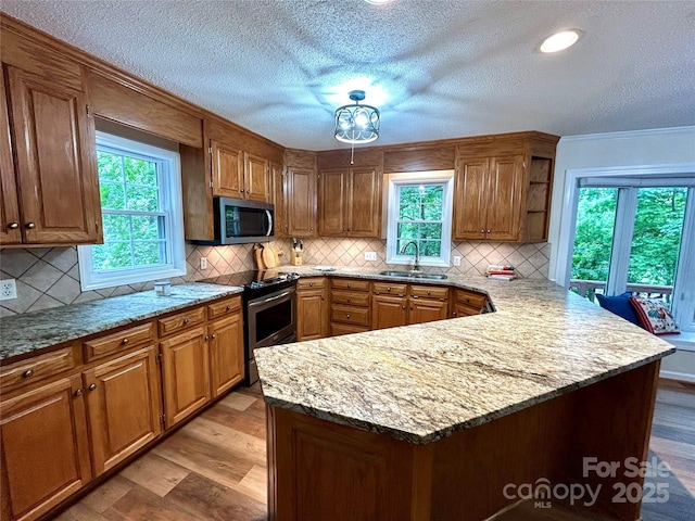 143 Uwharrie Ct Unit 1080, 1081, Mount Gilead, NC 27306 - kitchen with stainless steel appliances, a peninsula, healthy amount of natural light, brown cabinets, and a textured ceiling