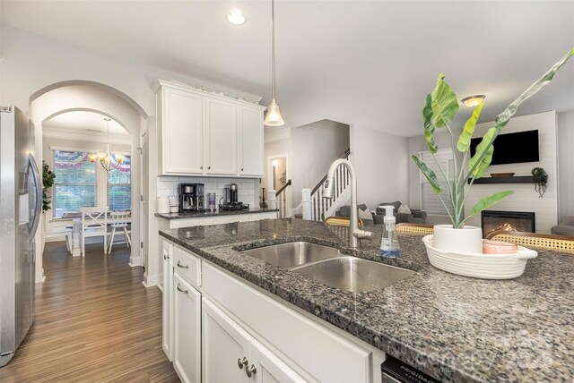 3332 Katherine Taylor Ct, Monroe, NC 28110 - kitchen featuring stainless steel refrigerator with ice dispenser, wood finished floors, a large fireplace, white cabinets, and arched walkways
