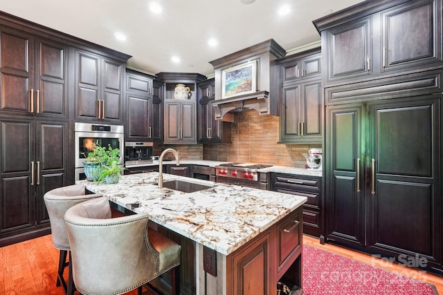 229 N Church St Unit 401, Charlotte, NC 28202 - kitchen featuring appliances with stainless steel finishes, light stone countertops, an island with sink, tasteful backsplash, and recessed lighting