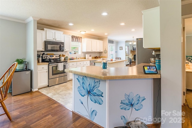 1828 Pine Hollow Pl, Hudson, NC 28638 - kitchen with black microwave, stainless steel range with electric stovetop, crown molding, light wood-style floors, and white cabinets