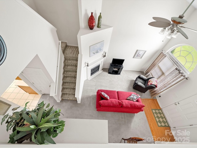 12415 Stratfield Place Cir, Pineville, NC 28134 - carpeted living area featuring a ceiling fan, stairway, and a fireplace with flush hearth