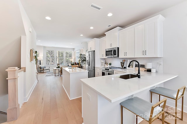 1223 E 16th St Unit 13, Charlotte, NC 28205 - kitchen featuring appliances with stainless steel finishes, a center island, light wood-style flooring, decorative backsplash, and recessed lighting