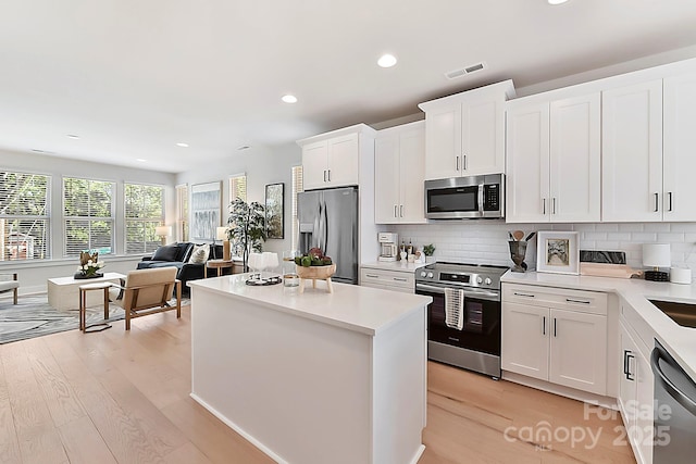 1223 E 16th St Unit 13, Charlotte, NC 28205 - kitchen with appliances with stainless steel finishes, light wood-type flooring, recessed lighting, decorative backsplash, and a kitchen island