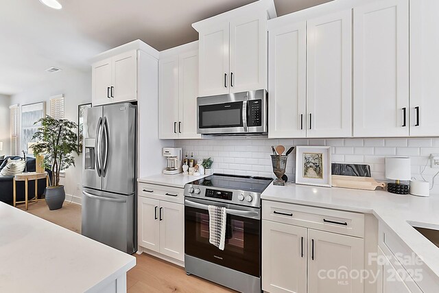 1223 E 16th St Unit 13, Charlotte, NC 28205 - kitchen with stainless steel appliances, light countertops, white cabinets, and backsplash